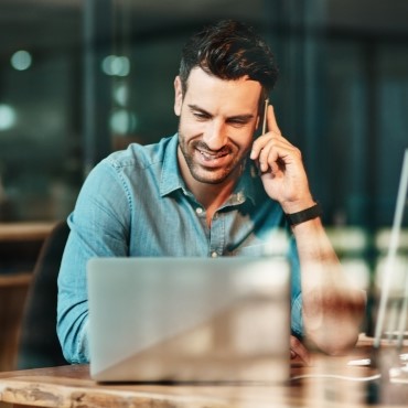 Man working on laptop and taking on the phone