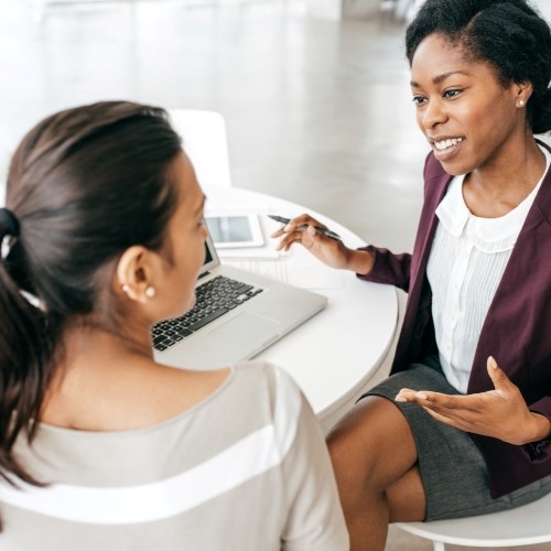 Human Resources representative and employee sitting down at table discussing total compensation for  job position