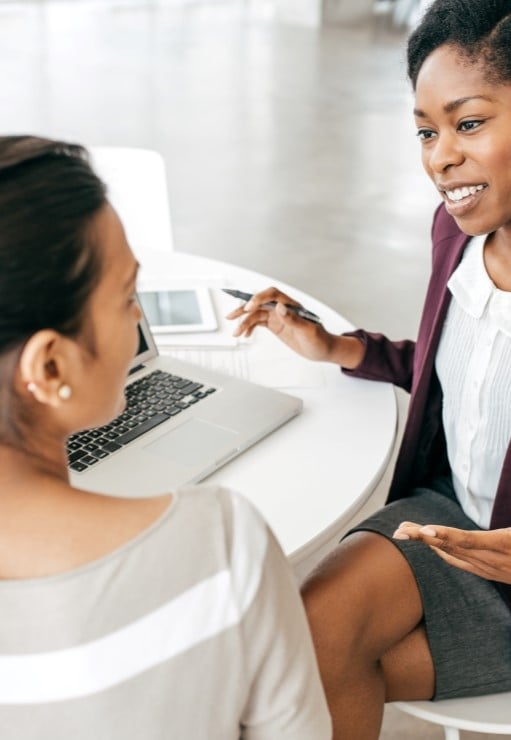 Human Resources representative and employee sitting down at table discussing total compensation for  job position